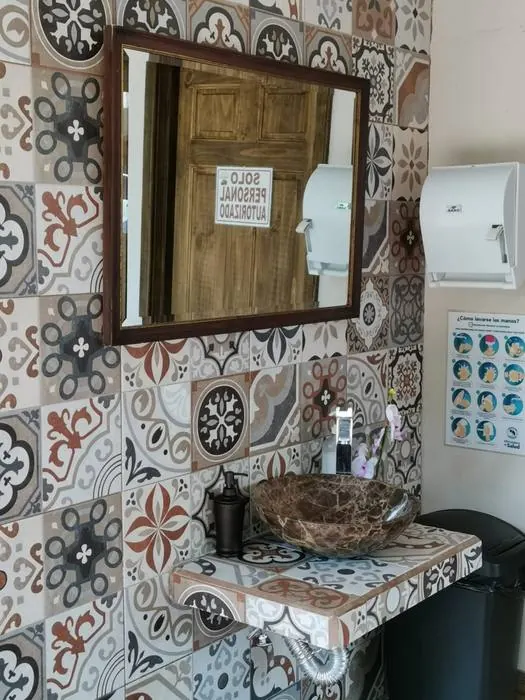 Lavamanos de piedra con azulejos estampados y espejo de marco de madera